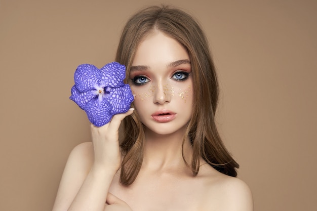 Portrait de beauté d'une femme avec une orchidée Vanda bleue dans sa main.