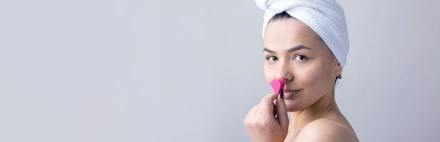 Portrait de beauté d'une femme en serviette blanche sur la tête avec une éponge pour un corps en vue d'un coeur rose