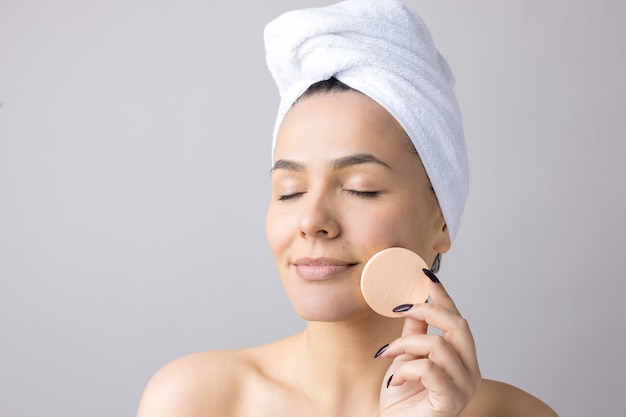 Portrait de beauté de femme en serviette blanche sur la tête avec une éponge pour un corps en vue d'un coeur rose