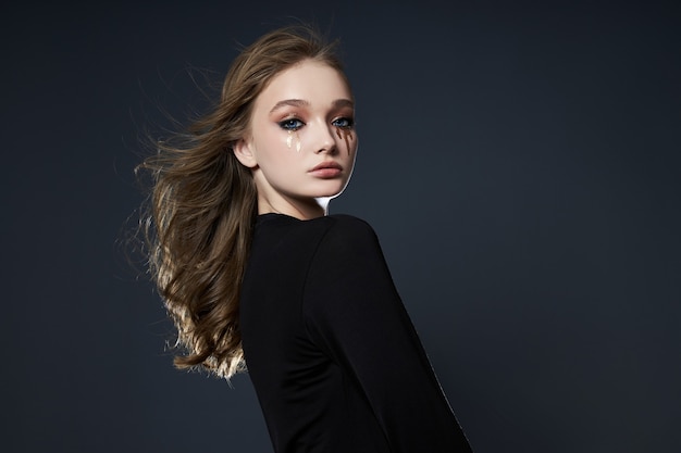 Portrait de beauté d'une fille avec un maquillage créatif, une femme qui pleure avec du mascara en paillettes