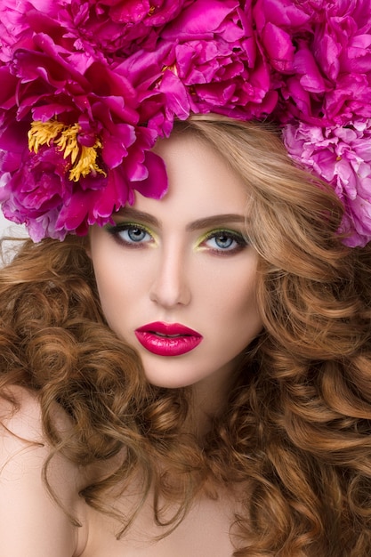 Portrait de beauté gros plan de jeune jolie fille avec une couronne de fleurs dans ses cheveux portant du rouge à lèvres rose vif. Maquillage d'été moderne et lumineux.