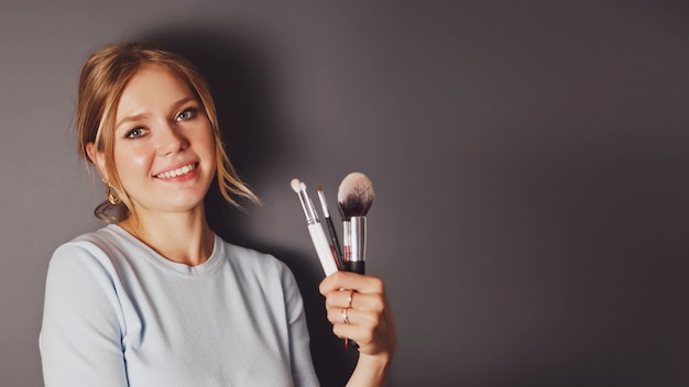 Portrait de beauté jeune blonde avec des pinceaux de maquillage