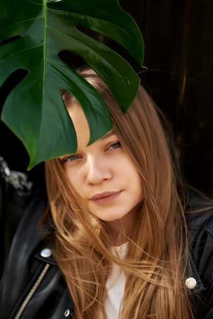 Portrait de beauté d'une jeune femme blonde séduisante saine debout isolé sur, tenant une fleur près de son visage