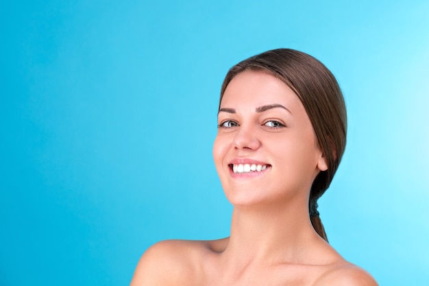 Portrait de beauté d'une jeune femme à moitié nue attrayante avec une peau parfaite en riant et en regardant la caméra isolée sur une surface bleue