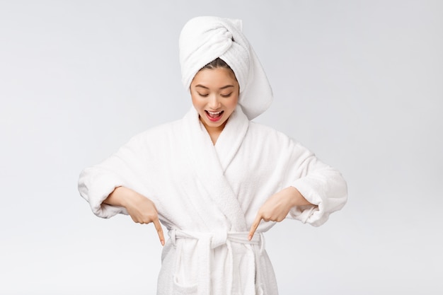 Portrait de beauté de la jeune femme montrant et pointant le doigt vers l'espace de copie vide, beauté asiatique en peignoir.