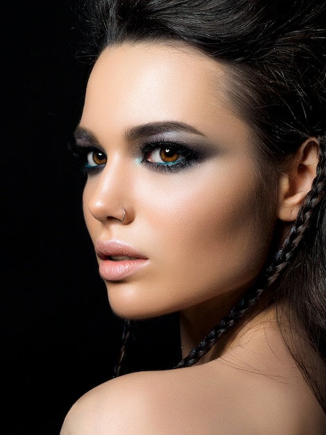 Portrait de beauté de jeune femme avec une peau parfaite et le maquillage du soir posant sur fond noir