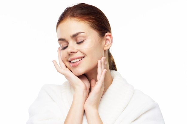 Portrait de beauté d'une jeune femme en robe de chambre sur fond blanc prend soin de la peau du