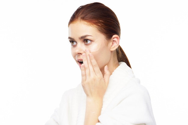 Portrait de beauté d'une jeune femme en robe de chambre sur fond blanc prend soin de la peau du