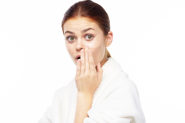 Portrait de beauté d'une jeune femme en robe de chambre sur fond blanc prend soin de la peau du