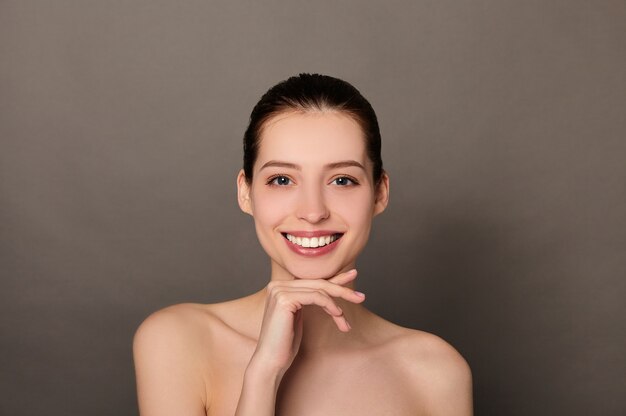 Portrait de beauté de jeune femme avec sa main sur son menton sur fond marron clair