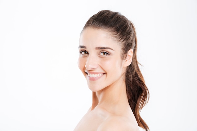 Portrait de beauté d'une jeune femme souriante regardant à l'avant sur un mur blanc