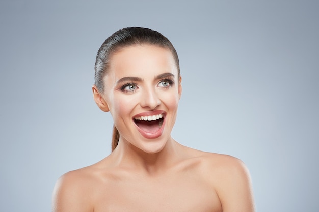 Photo portrait de beauté d'une jeune fille souriante heureuse en levant. tête et épaules de belle femme joyeuse avec un large sourire. maquillage naturel, studio, vraies émotions