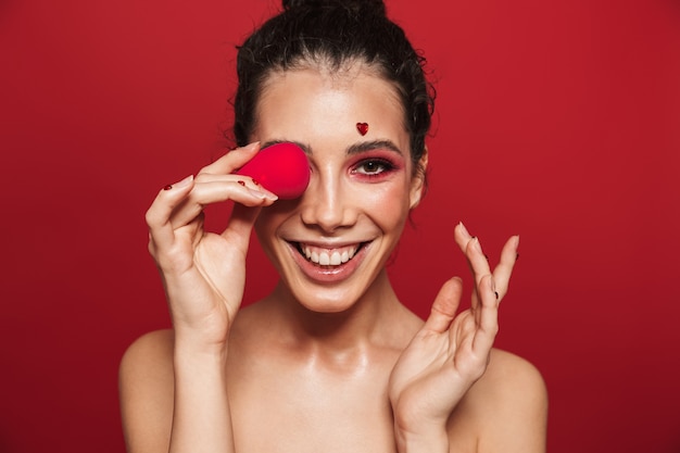 Portrait de beauté d'une jolie jeune femme aux seins nus portant du maquillage debout isolé