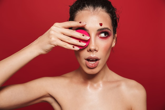 Portrait de beauté d'une jolie jeune femme aux seins nus portant du maquillage debout isolé