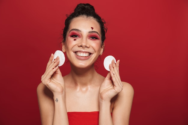 Portrait de beauté d'une jolie jeune femme aux seins nus portant du maquillage debout isolé