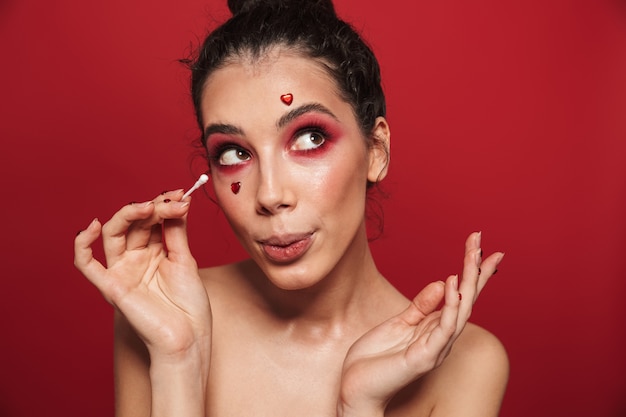 Portrait de beauté d'une jolie jeune femme aux seins nus portant du maquillage debout isolé