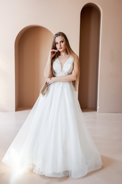 Portrait de beauté de la mariée portant une robe de mariée à la mode avec des plumes avec un maquillage de luxe