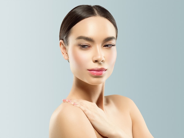 Portrait de beauté de plan rapproché cosmétique de femme avec des mains, cheveux sains de peau de soin sur le fond de couleur grise