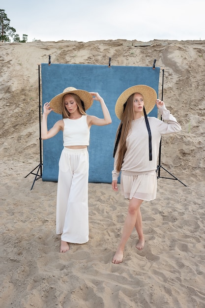 Portrait de beauté en plein air sur le sable en face de fond bleu, jeunes jolis jumeaux