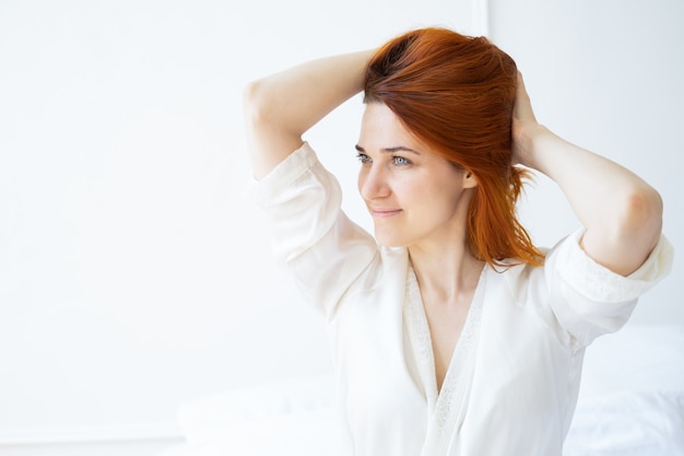 Portrait de beauté souriant femme gingembre moyen âge n visage frais et mains en robe de soie dans une salle lumineuse