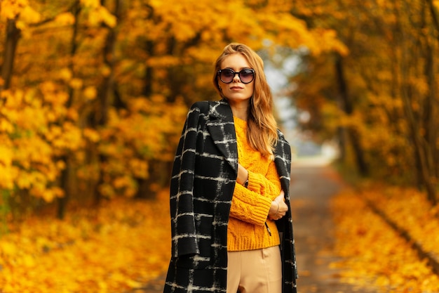 Portrait Beautiful Slavic GirlÃƒÂ¢Ã‚Â€Ã‚Â‹ dans des lunettes à la mode avec un pull et un manteau tricotés vintage se promène dans un parc coloré d'automne avec un feuillage jaune vif