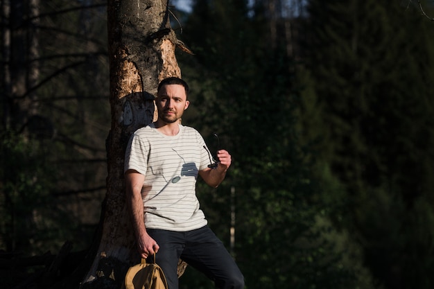 Portrait de beaux-arts d'un homme hipster portant des lunettes de soleil dans une forêt.