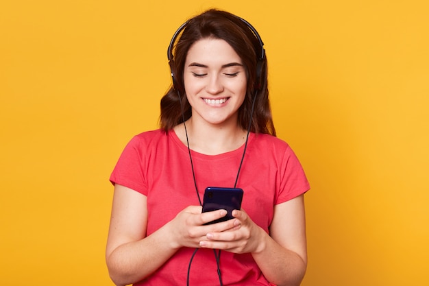 Portrait de beaux cheveux foncés, écouter de la musique sur téléphone mobile