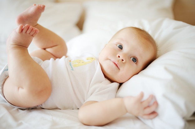 Portrait de bébé aux yeux bleus. Un enfant au repos sur un lit