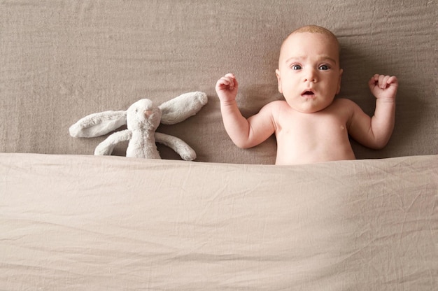 Portrait d'un bébé garçon avec un jouet allongé sur le lit