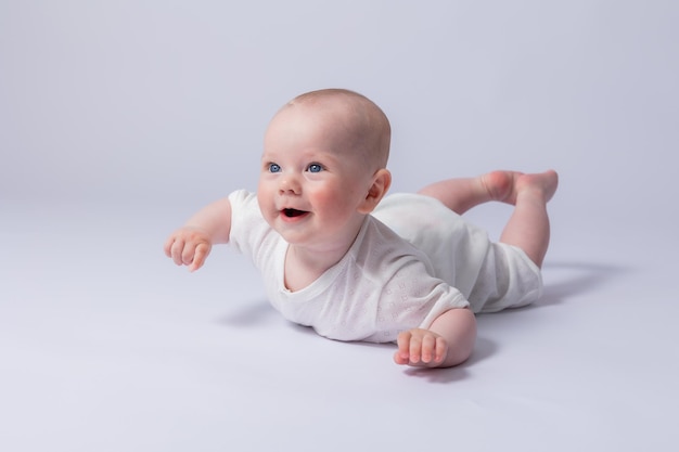 Portrait d'un bébé mignon de 5 mois dans un body blanc sur fond blanc dans le studio souriant regardant dans le cadre Baby39s santé bébé nouveau-né espace pour le texte