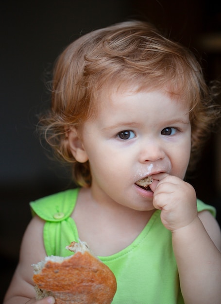 Portrait de bébé mignon avec du pain dans ses mains en train de manger. Enfant en bas âge mignon mangeant un sandwich, concept d'auto-alimentation.