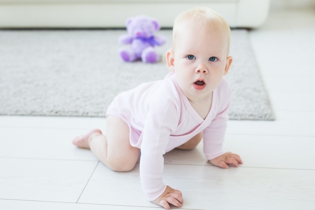 Portrait d'un bébé mignon rampant et riant sur le sol à la maison