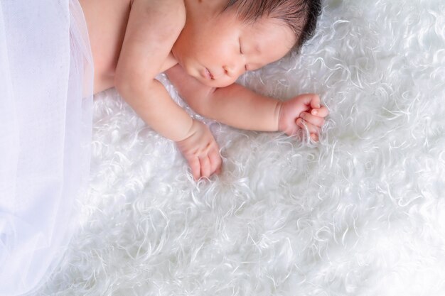 Portrait d'un bébé d'un mois endormi, nouveau-né sur une couverture blanche. Concept portrait studio mode nouveau-né.