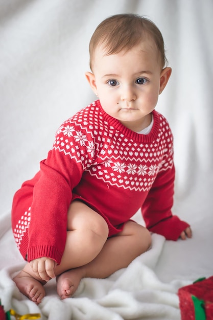 Portrait d'un bébé avec un pull de Noël dans un studio avec un fond blanc