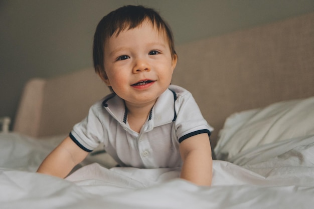 portrait d'un bébé souriant d'un an sur le lit à la maison