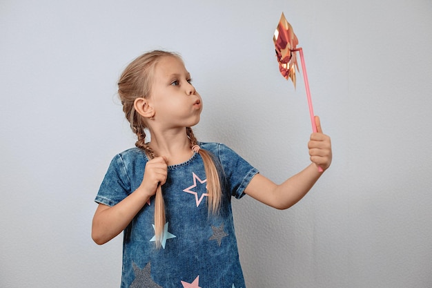 Portrait d'un bel enfant adorable soufflant sur un jouet tournant dans les airs tout en le tenant dans sa main. Concept amusant. photo avec du bruit