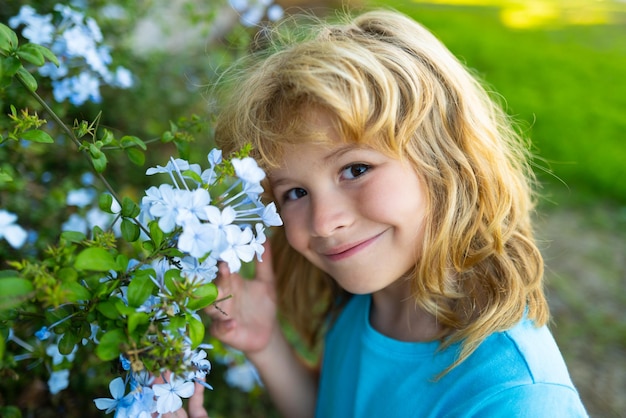 Portrait d'un bel enfant dans le jardin fleuri d'été Enfant heureux sur le pré avec des fleurs blanches Chaude soirée d'été Enfants et nature