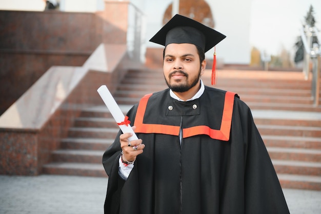 Portrait d'un bel étudiant diplômé indien dans la lueur de l'obtention du diplôme avec diplôme