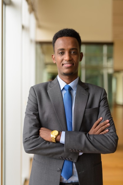 Portrait d'un bel homme d'affaires africain portant un costume et une cravate avec les bras croisés, tir vertical