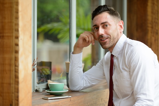 Portrait de bel homme d'affaires avec barbe de chaume se détendre au café en plein air