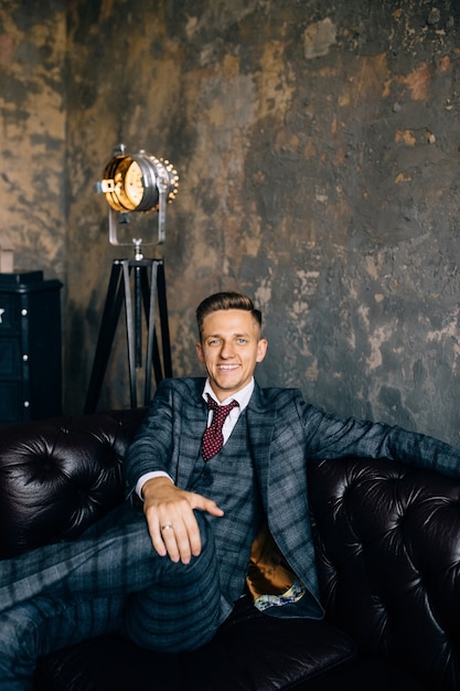 Portrait d'un bel homme d'affaires en costume sur un canapé en cuir vintage de luxe