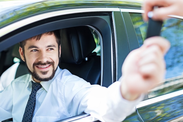 Portrait d'un bel homme d'affaires heureux au volant de sa voiture