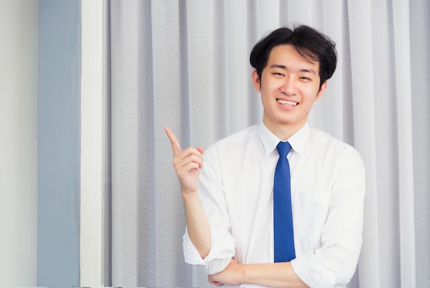 Portrait d'un bel homme d'affaires heureux confiant portant une chemise pose debout souriant à la caméra, il pointe le doigt vers l'espace de côté