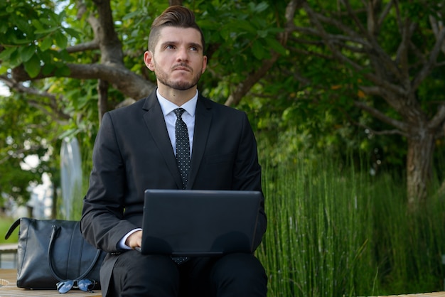 Portrait de bel homme d'affaires hispanique barbu avec la nature dans la ville en plein air