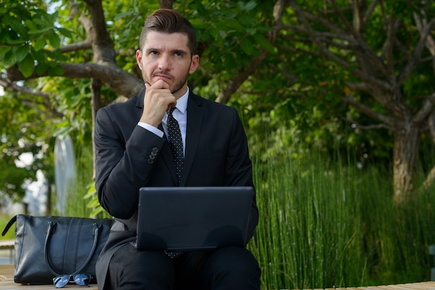 Portrait de bel homme d'affaires hispanique barbu avec la nature dans la ville en plein air