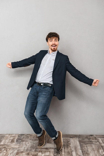 Portrait d'un bel homme d'affaires jeune émotionnel isolé sur la danse de mur gris.