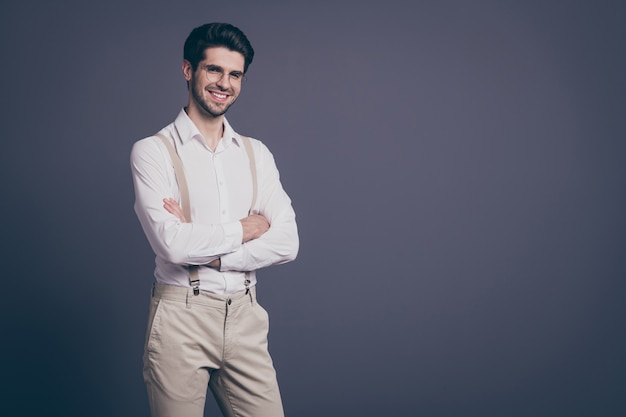 portrait de bel homme d'affaires les mains croisées à pleines dents rayonnant chef souriant habillé formel chemise blanche bretelles beige pantalon spécifications.