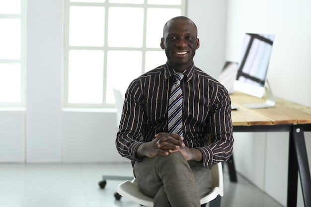 Portrait d'un bel homme d'affaires noir assis au bureau