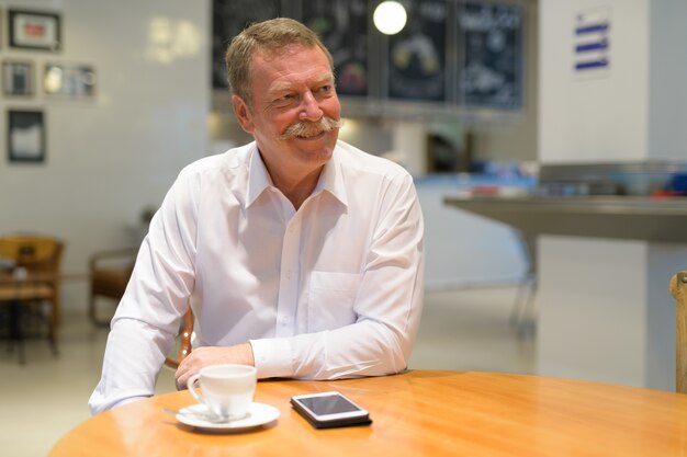 Portrait de bel homme d'affaires senior avec moustache au café