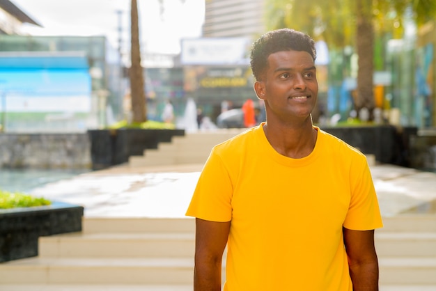 Portrait d'un bel homme africain noir portant un t-shirt jaune à l'extérieur de la ville de Bangkok, Thaïlande